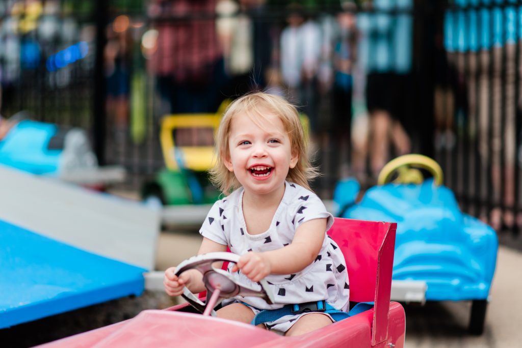 a little girl laughing while playing at kiddie park